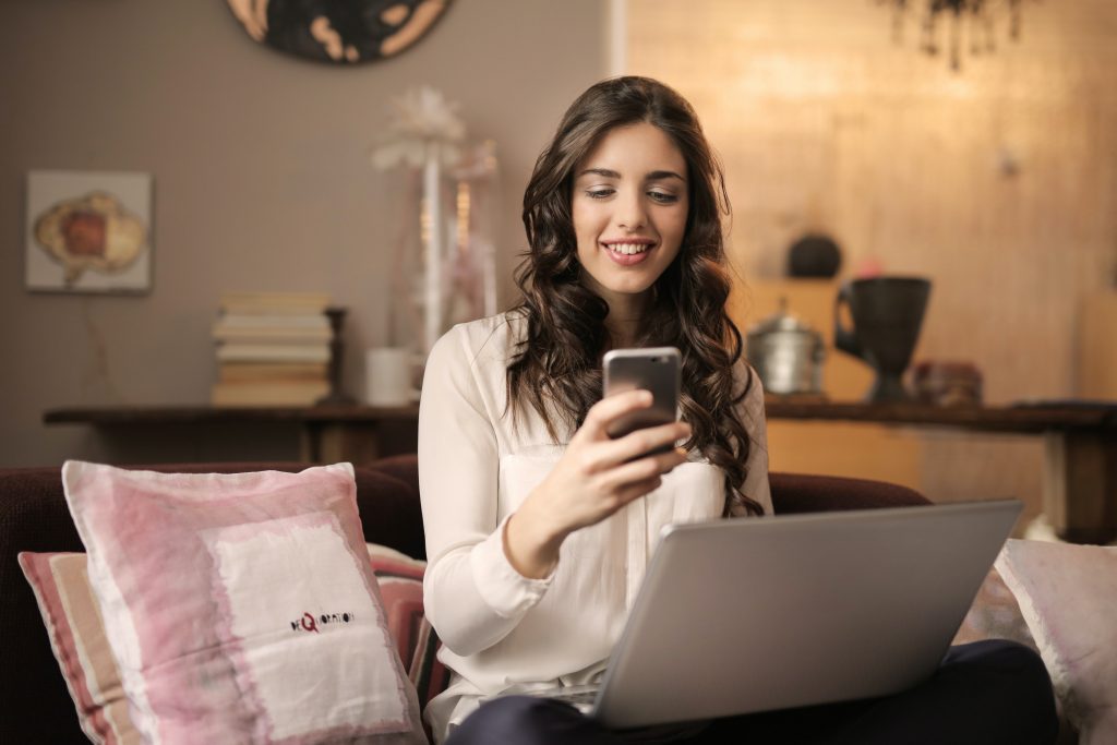 A woman carrying a phone and sitting in front of her laptop